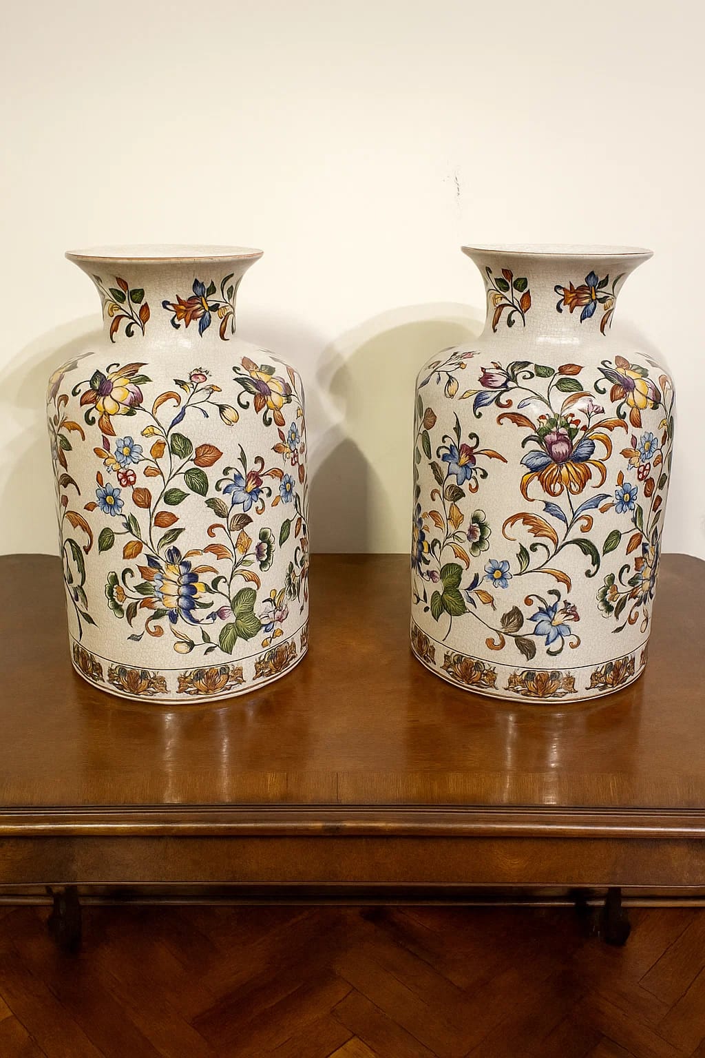 A matched pair of Chinese-floral ceramic vases covered in vibrant, multicolored vine and blossom ...