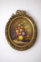 A lush bouquet in a gilded oval frame