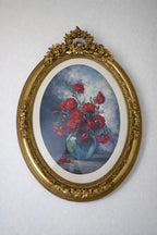 A showpiece wall plaque: ornate gold oval frame, lush floral artwork