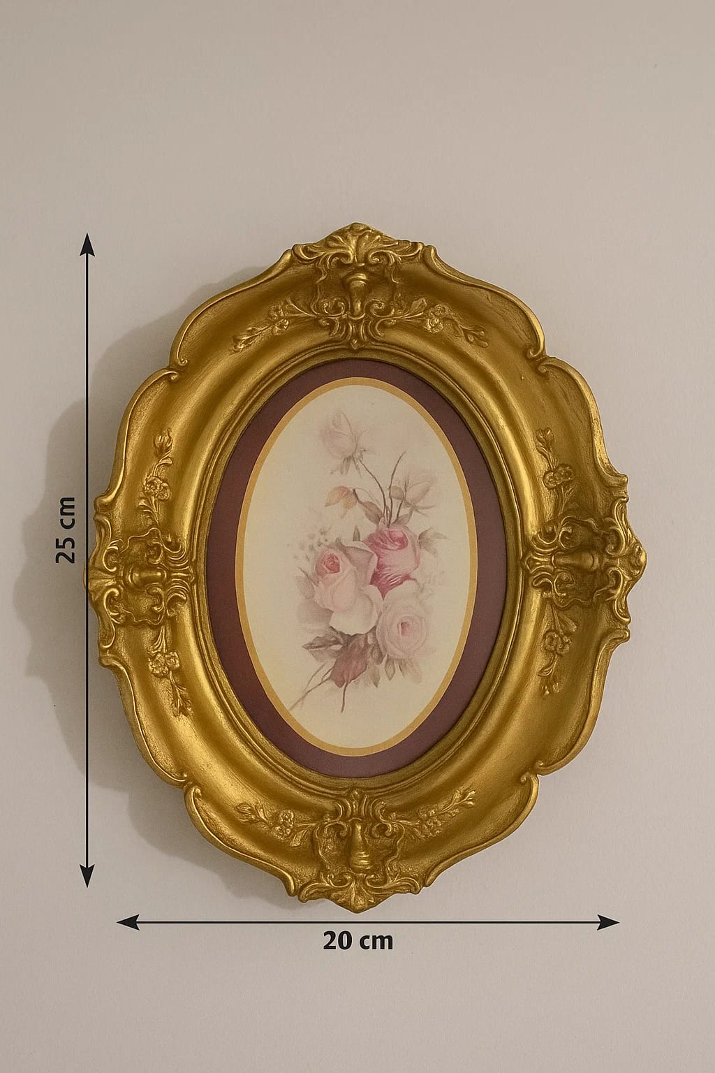 A pair of vintage-style oval frames in a richly gilded finish, each with a delicate floral cente...